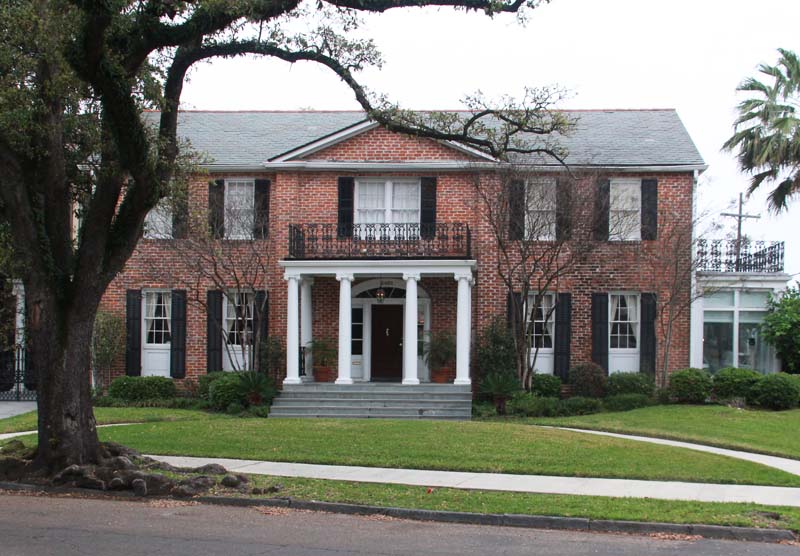 Southern New Orleans brick house with black exterior shutters.