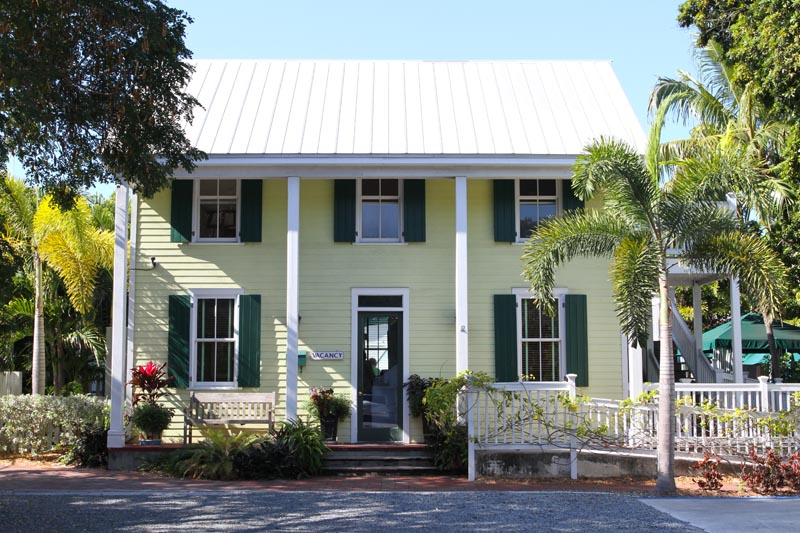 Green exterior shutters installed on a yellow tropical house in Florida.