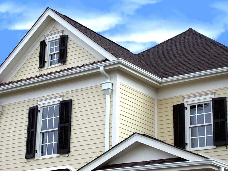 Exterior black shutters installed on a yellow house.