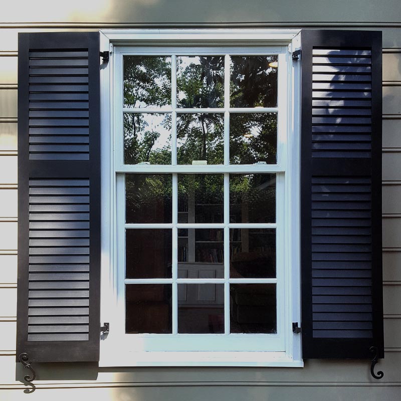 Louvered black shutters installed on exterior windows.
