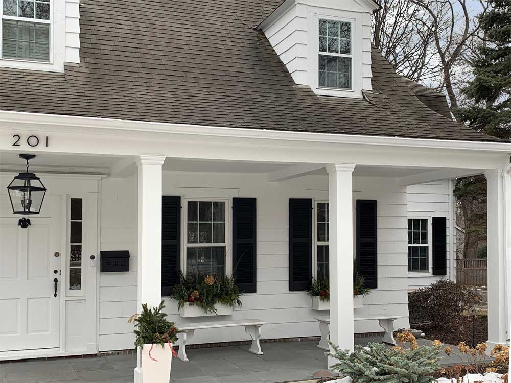 Outdoor wood famhouse shutters installed on porch.