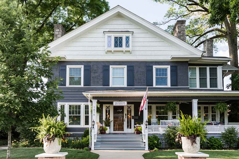 Solid exterior panel shutters installed on gray house with white trim.