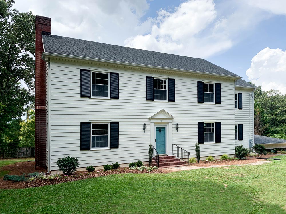 Black louvered shutters installed on a colonial white house.