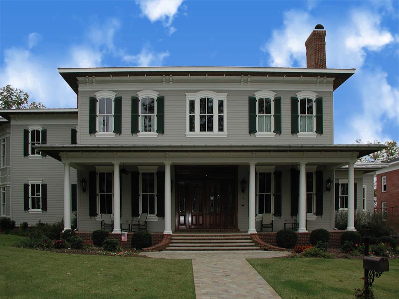 Green arch top shutters installed on house windows.