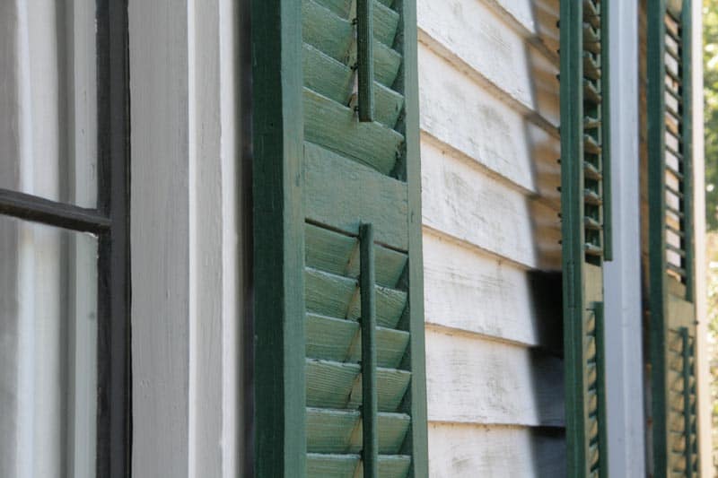 Exterior green shutters on a white house.