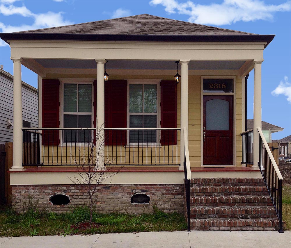 Red exterior pine wooden shutters on yellow shotgun house.