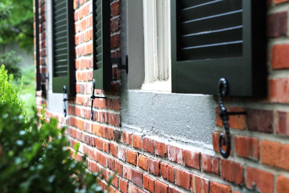 Black wood exterior shutters with s-pattern shutter dogs.