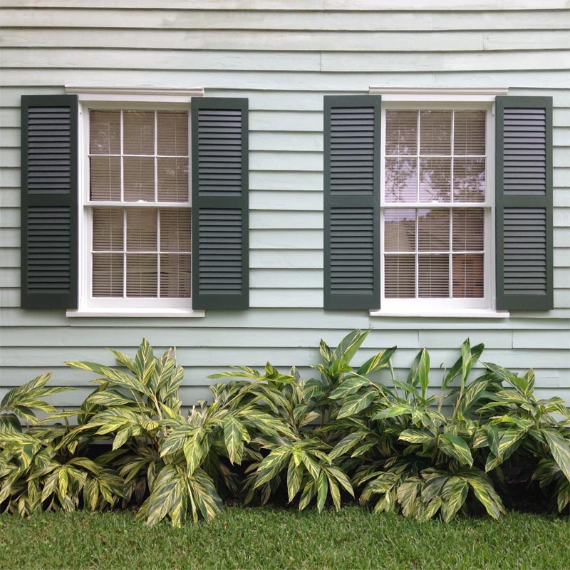 Louvered green pine shutters installed on outside windows.