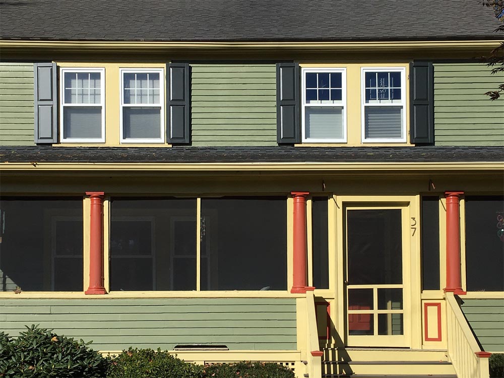 Green house with black raised panel exterior shutters.