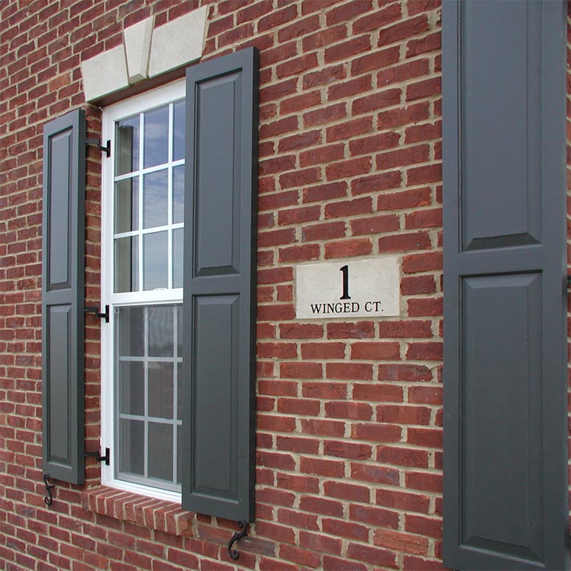 Raised panel exterior shutters installed on brick.