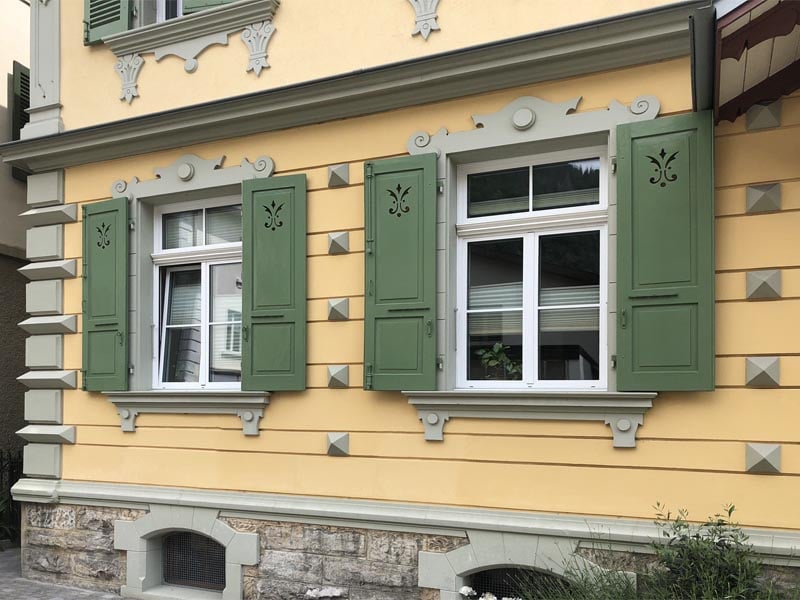 Raised panel shutters with fleur de lis cutouts in Switzerland.