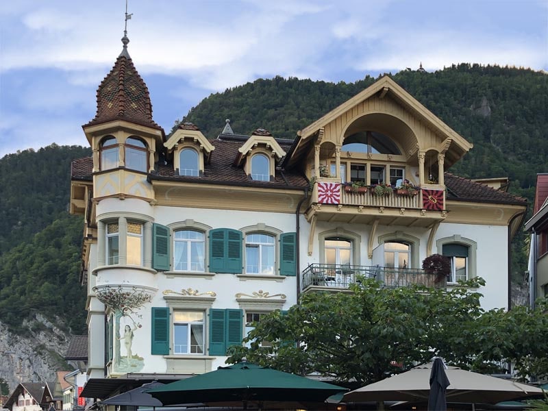 Green combination arch top shutters on Swiss hotel with louvers and flat panels.