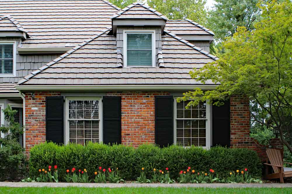 Black wood ShutterLand exterior shutters installed on a brick house.