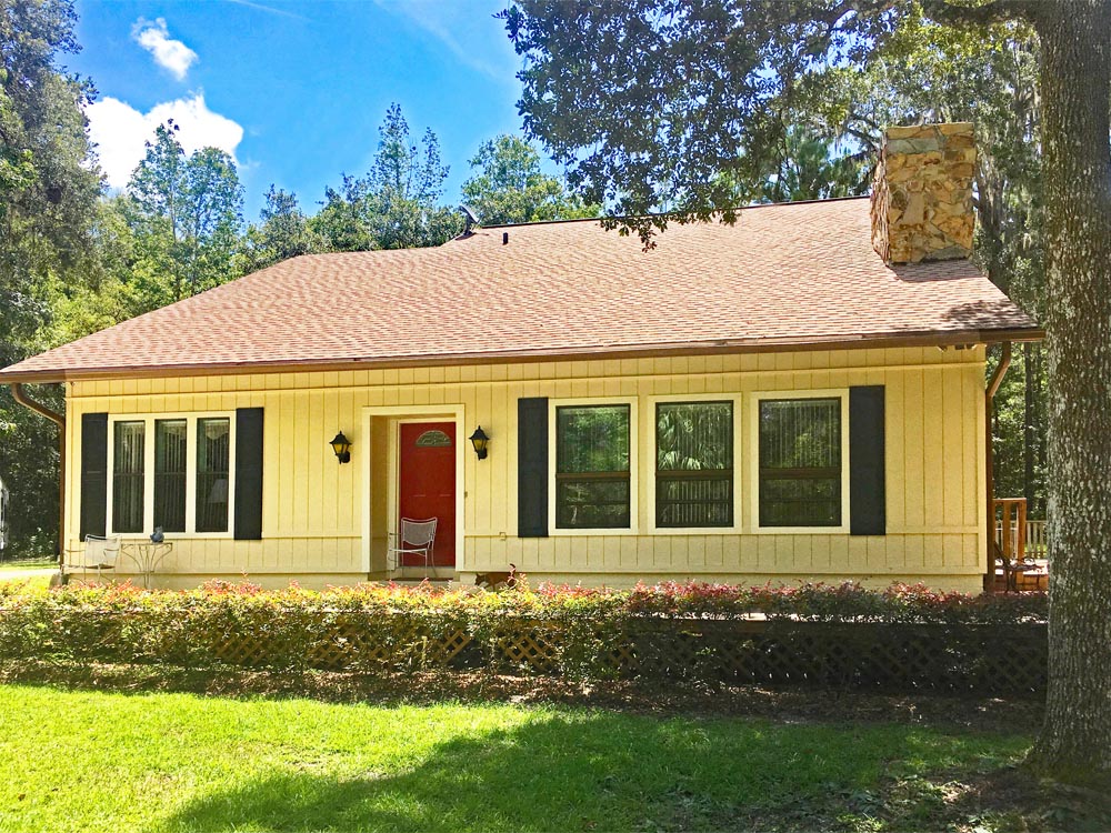 Yellow house with dark vinyl shutters on outdoor windows.