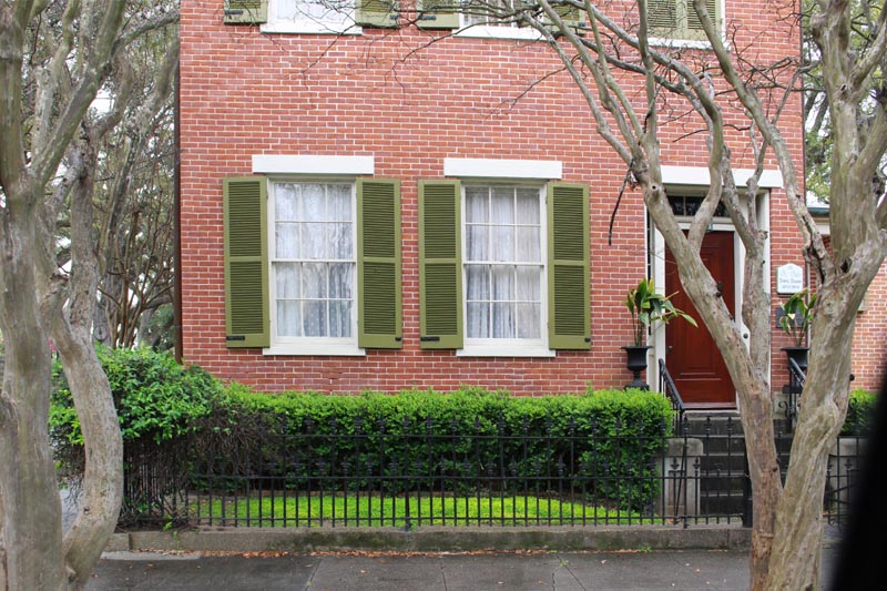 Southern outdoor green shutters installed on a brick house.