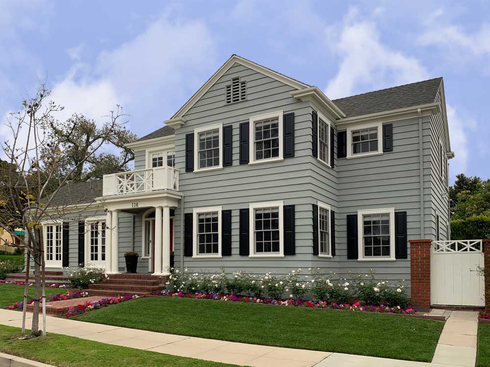 Gray house with black raised panel exterior shutters.