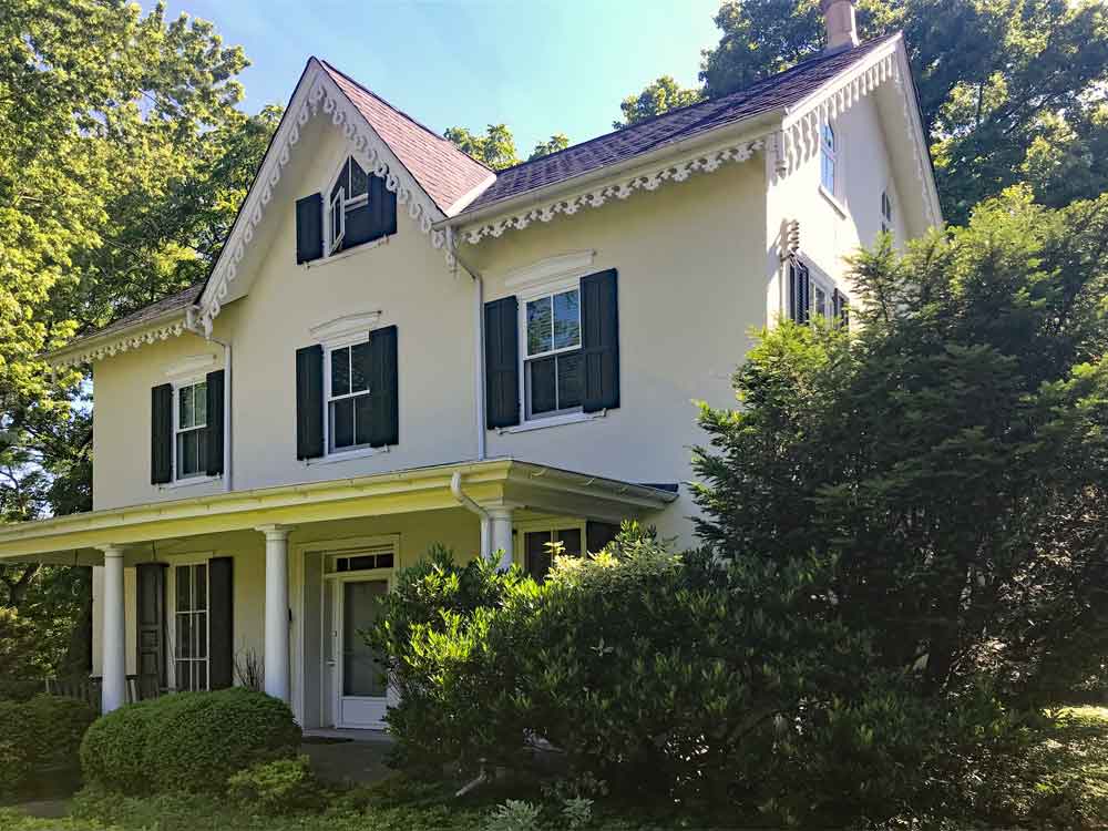 Historic house with black louvered shutters with a tilt bar.