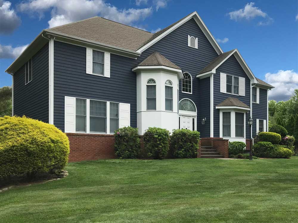 White raised panel exterior vinyl shutters on blue house.