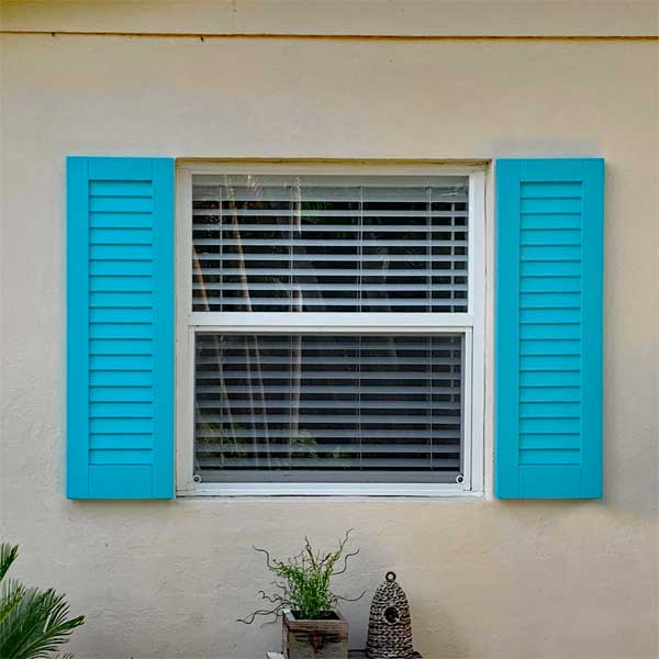 Outdoor composite louvered shutter installed on a double-hung window.