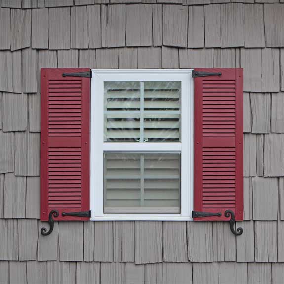 Louvered outside vinyl shutter installed on an exterior house window.