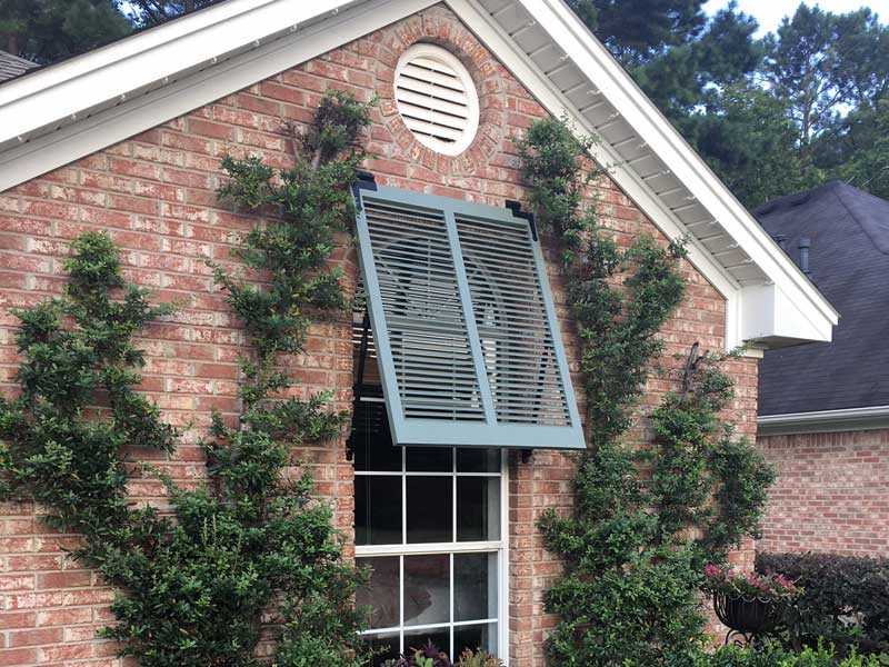 Wood bahama shutters installed with exterior hinges.