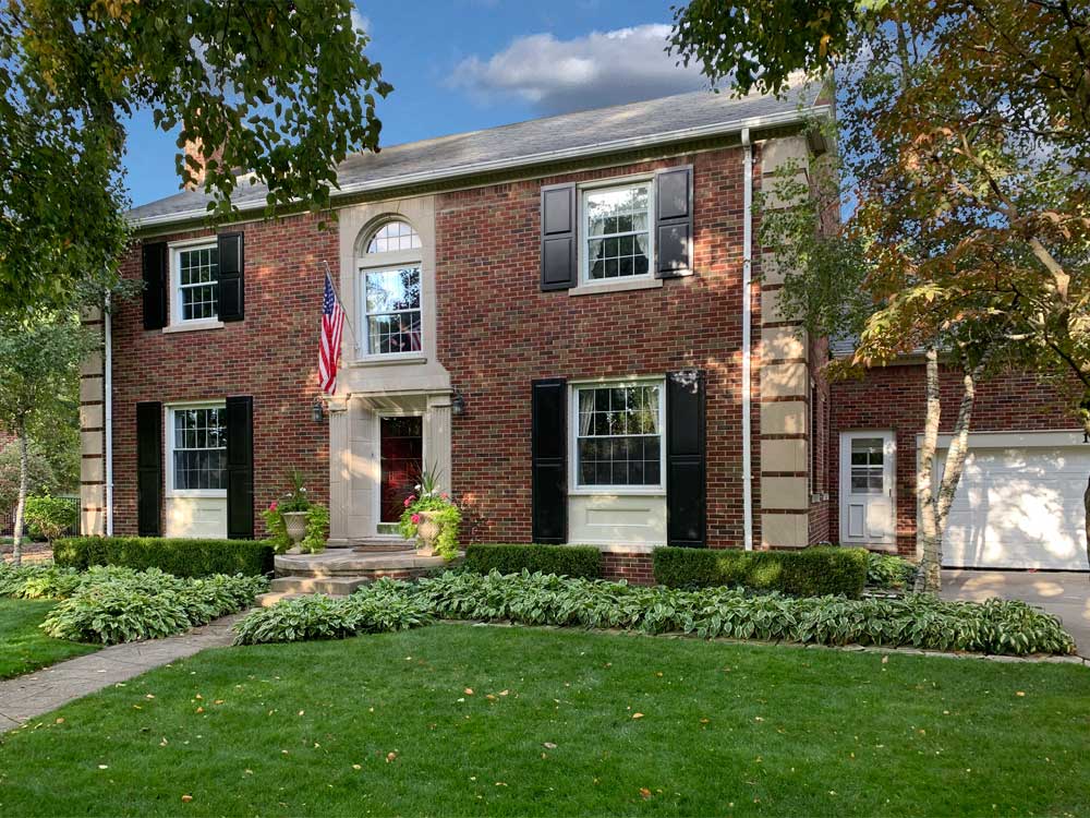 Raised panel black shutters installed on a brick house.