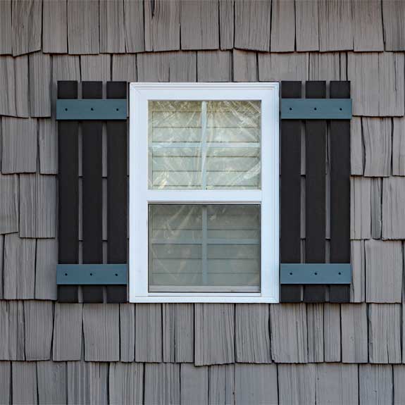 Installed vinyl board and batten exterior shutters on a window.