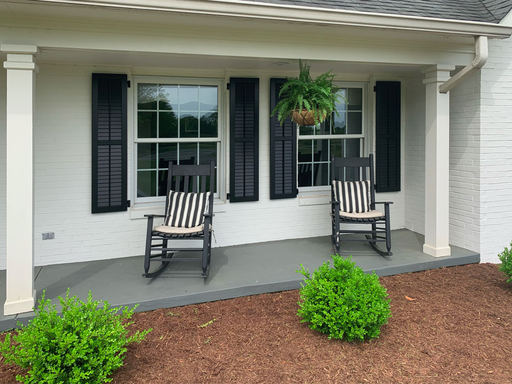 Front porch exterior shutters made from composite material and installed with hinges.