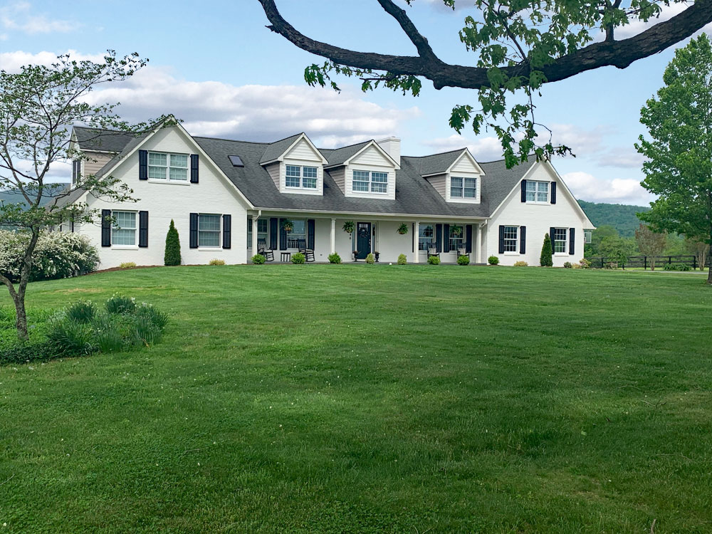 Composite exterior louvered shutters with faux tilt bars on white house.