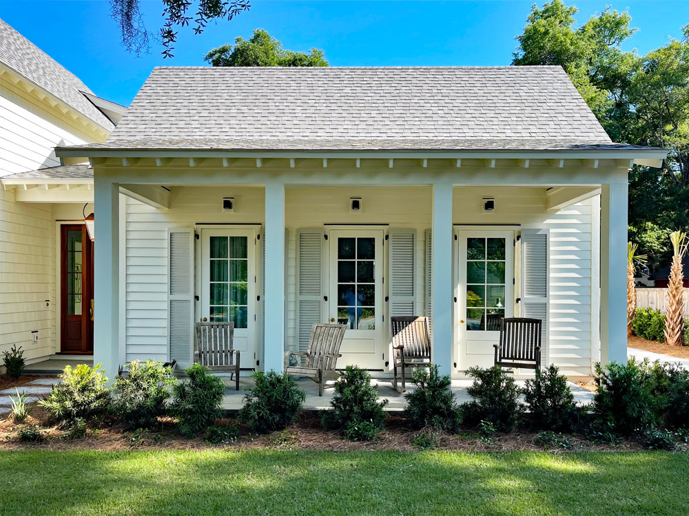 Off-white louvered wood shutters installed on a white house.