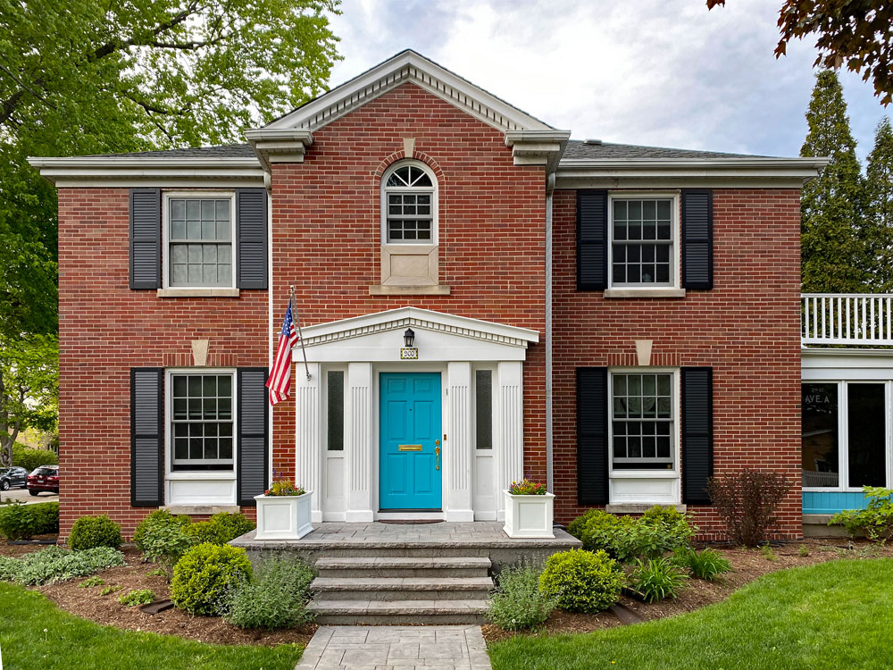 Black composite louvered exterior shutters on a brick house.