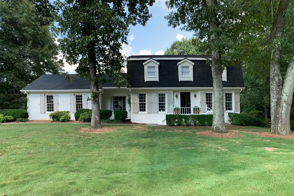 Outdoor white house with gray louver shutters installed.