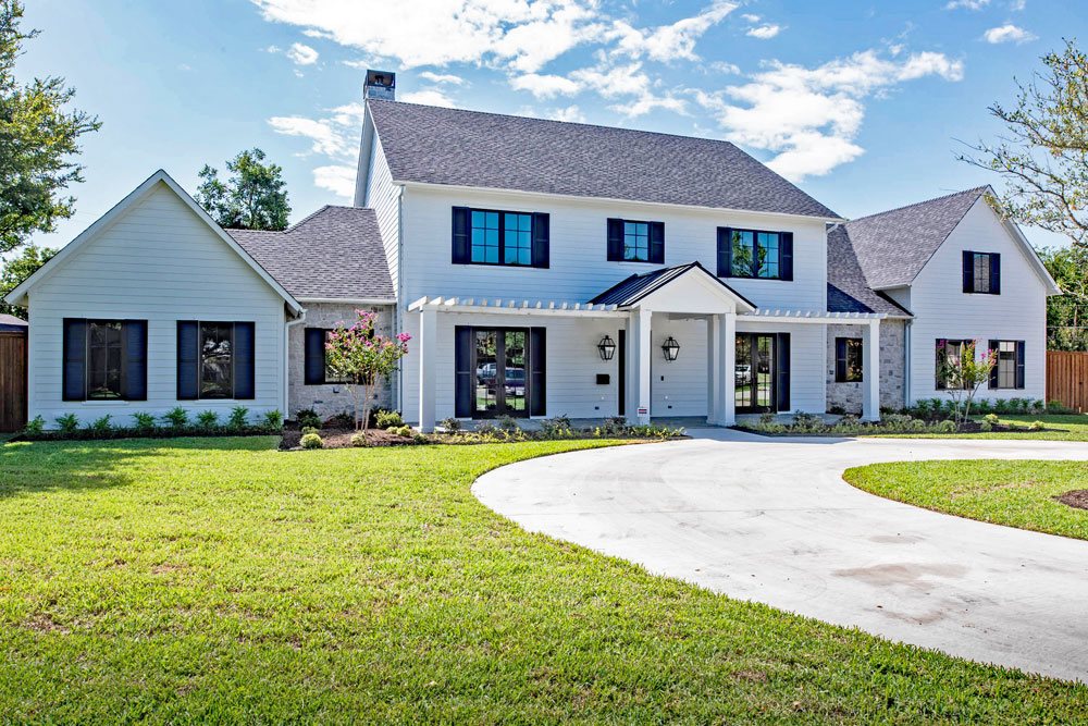 Louvered composite black shutters installed on a white farmhouse.