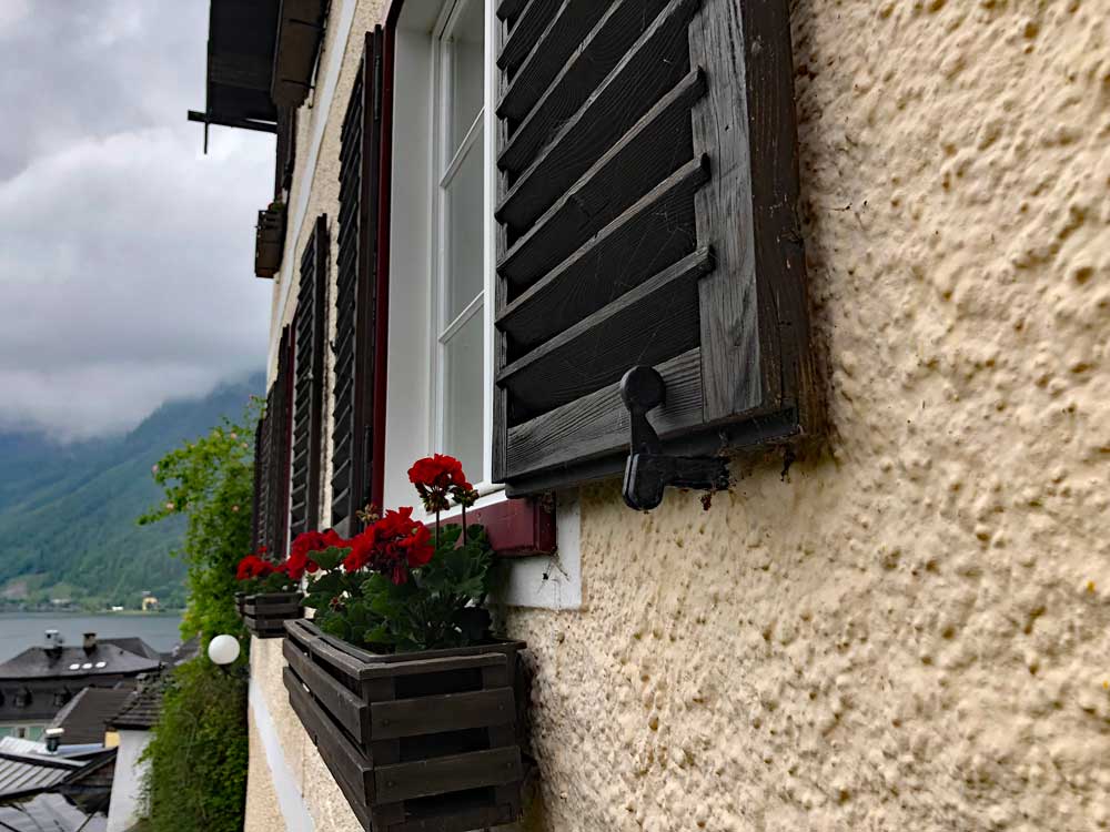 Drop-down shutter dogs used in a beautiful mountain village with flowers.