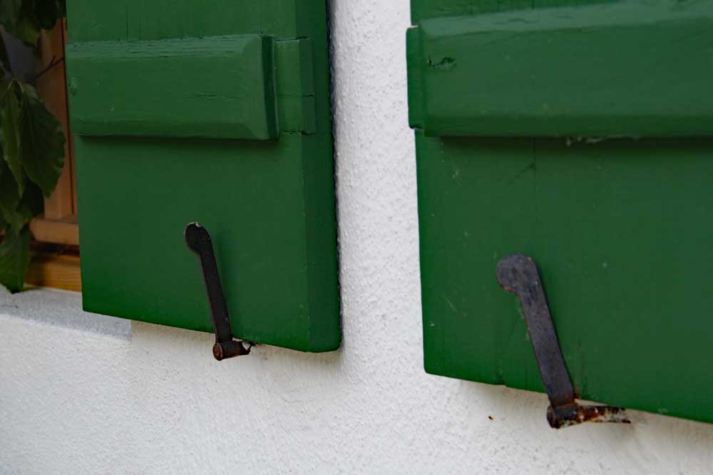 Rotating lever tiebacks holding board and batten shutters agains a house.