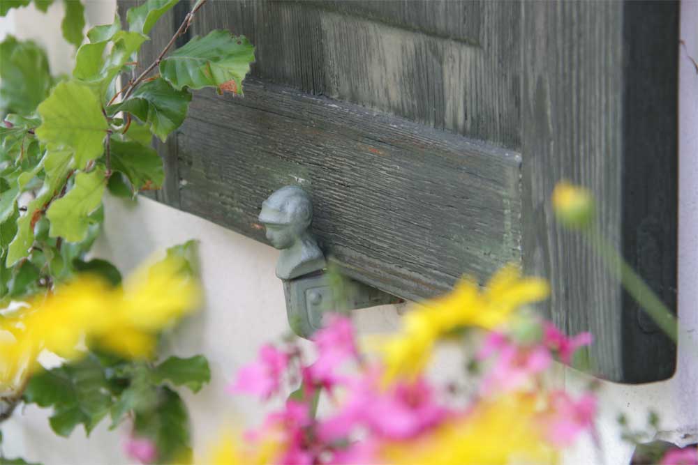 Soldier tieback holding a wood raised panel shutter around flowers.