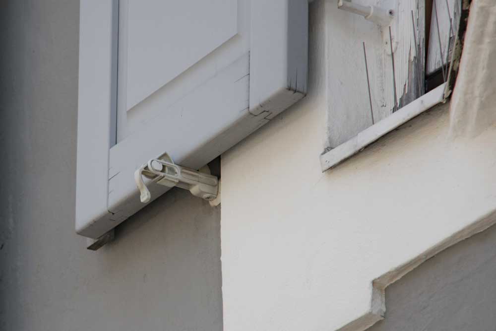 Push button shutter that releases when pressed and automatically latches when the shutter is closed.