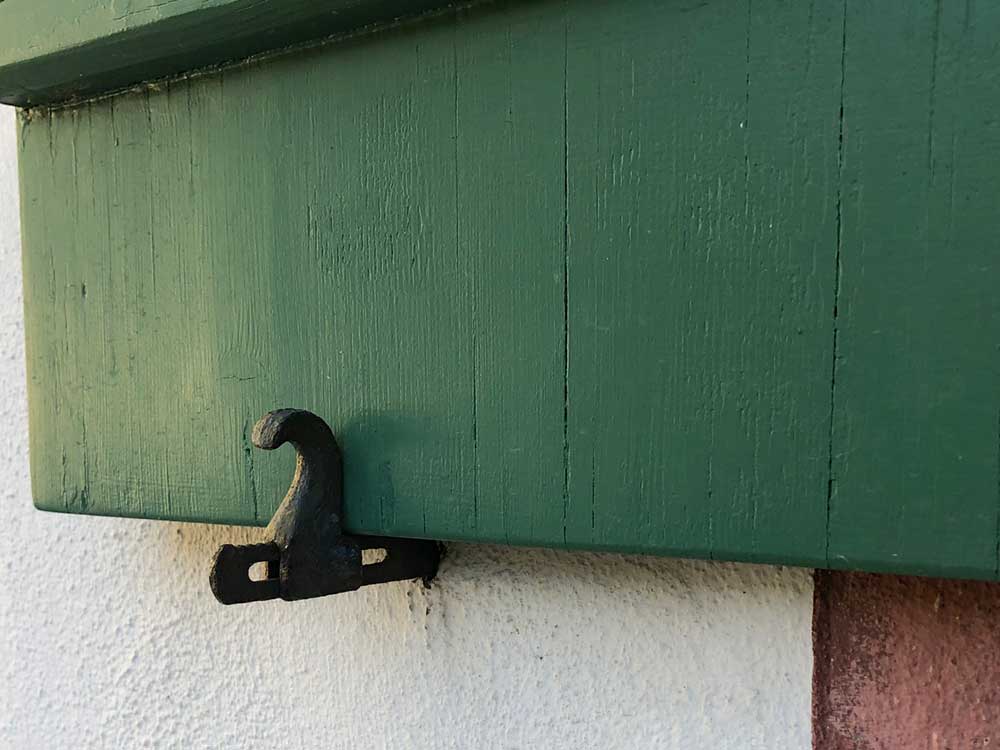Sliding wave style shutter dog holding back a board and batten shutter.