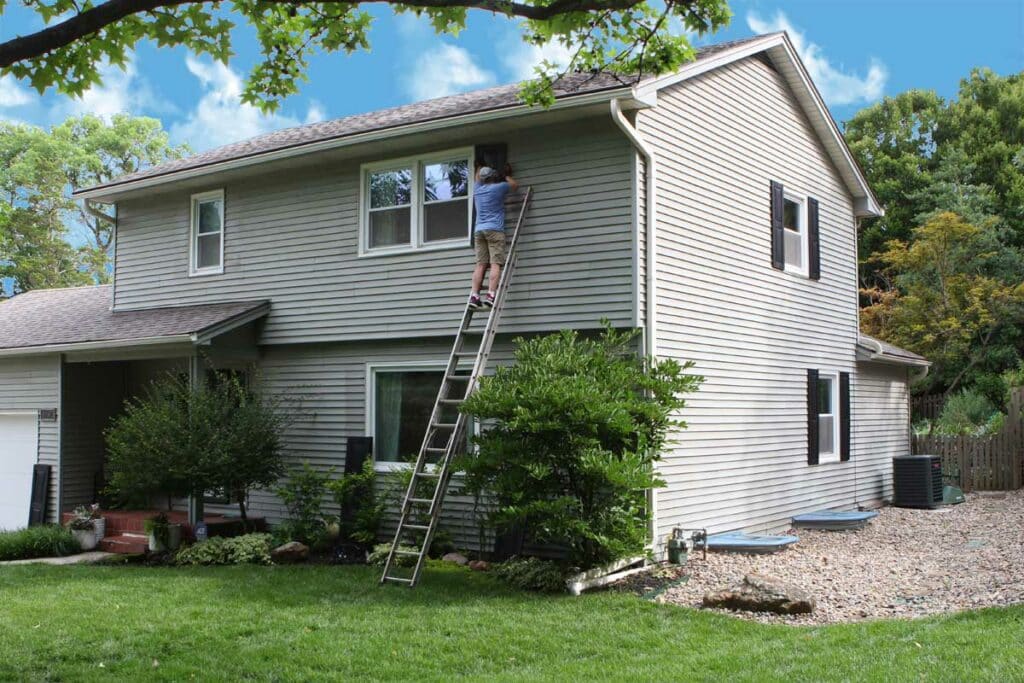 Install black vinyl exterior shutters on brown home.