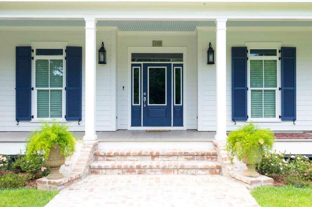 Blue PVC shutters installed on a white house with hardware.