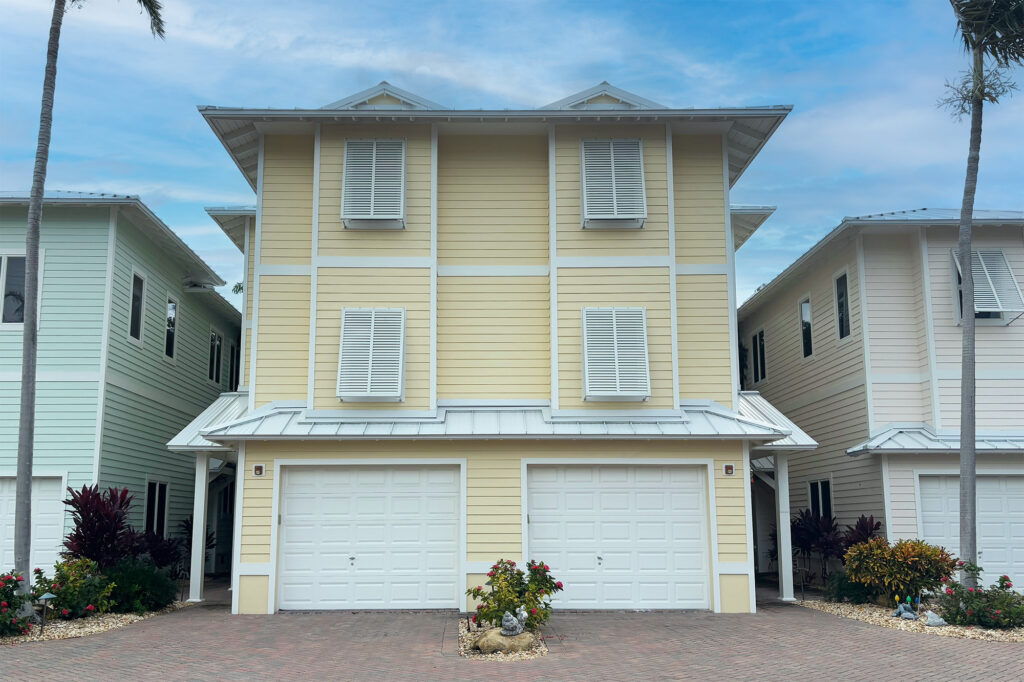 Bahama hurricane shutters installed on a yellow house along the Florida coast.