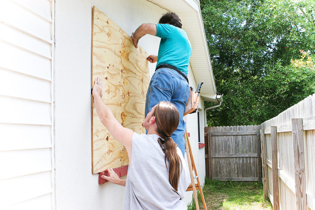 Installing hurricane plywood shutters in preparation for a storm.