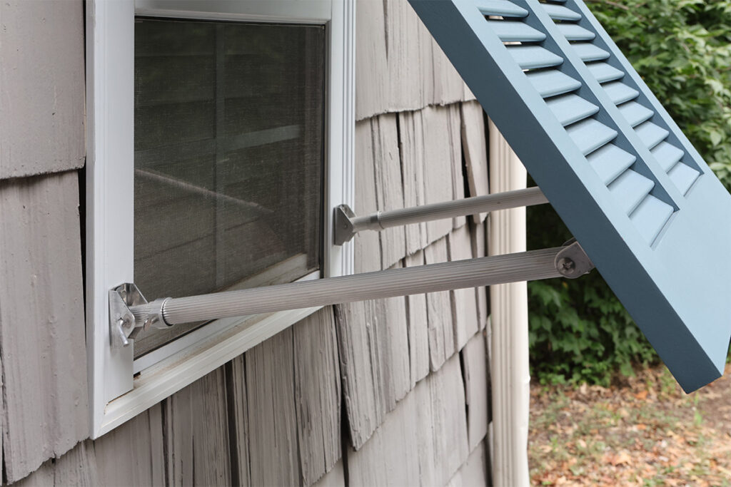 Side view of support arm hardware that keeps exterior Bahama shutters in an open position.