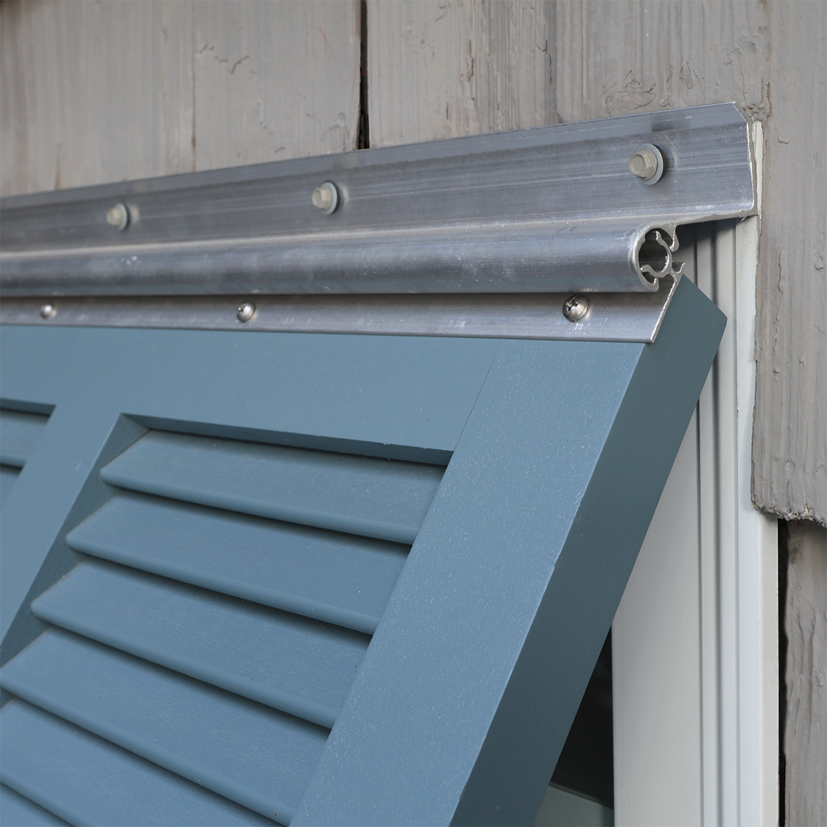Silver aluminum top hinge of a Bahama shutter.