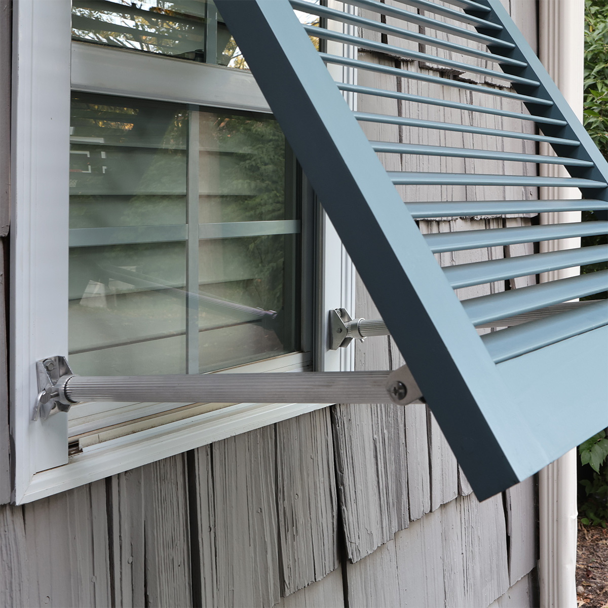 Support arm holding a wood Bahama shutter in an open position.